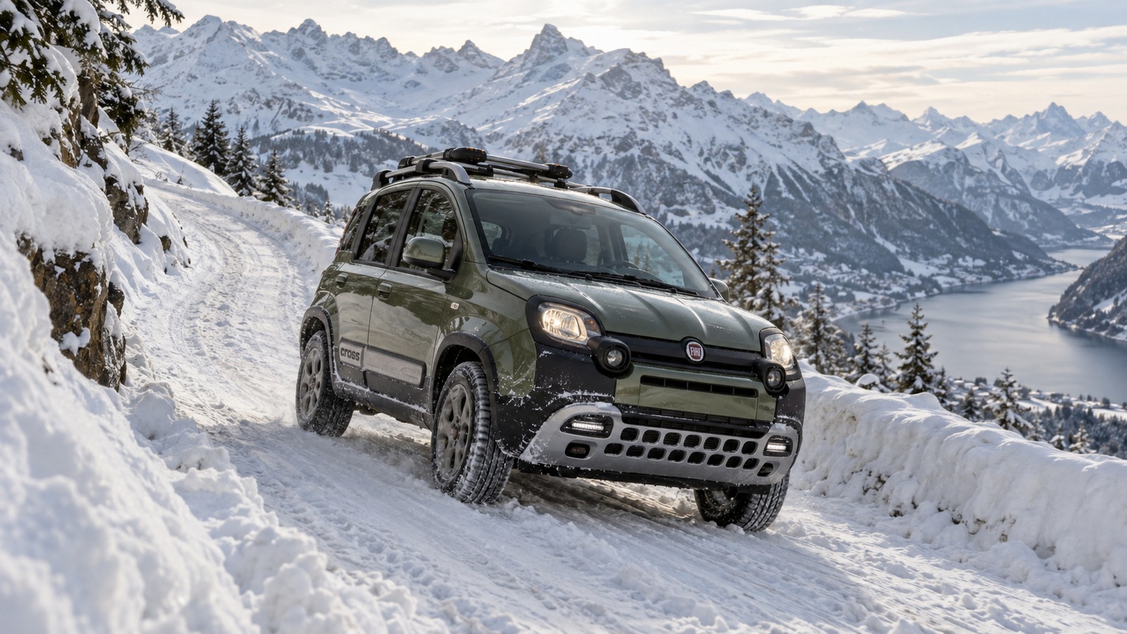 Ein Fiat Panda Cross fährt auf einer schneebedeckten Bergstrasse über einem Alpensee.
